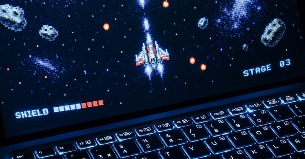 A classic arcade space shooter game displayed on a laptop with illuminated keyboard, showing retro graphics.