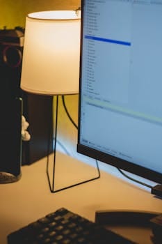 A warm and inviting workspace displaying a lit lamp and computer monitor on a tidy desk.