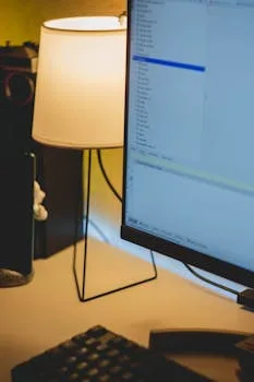 A warm and inviting workspace displaying a lit lamp and computer monitor on a tidy desk.