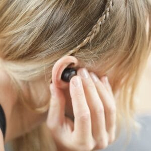 Someone listening to music with sleek earbuds while working at a café