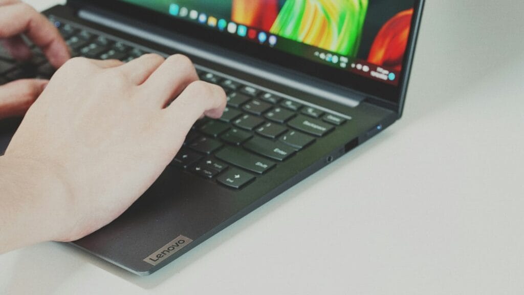 Hands typing on a Lenovo laptop keyboard
