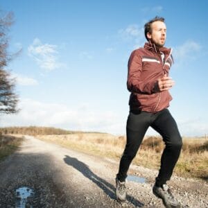 Runner wearing sporty open‑ear earbuds with a translucent charging case