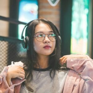 Woman wearing white Sennheiser Momentum 5 headphones while studying at a cafe
