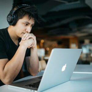 Person wearing over‑ear headphones while focusing on a laptop screen
