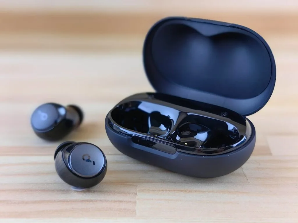Black wireless earbuds on a wooden table