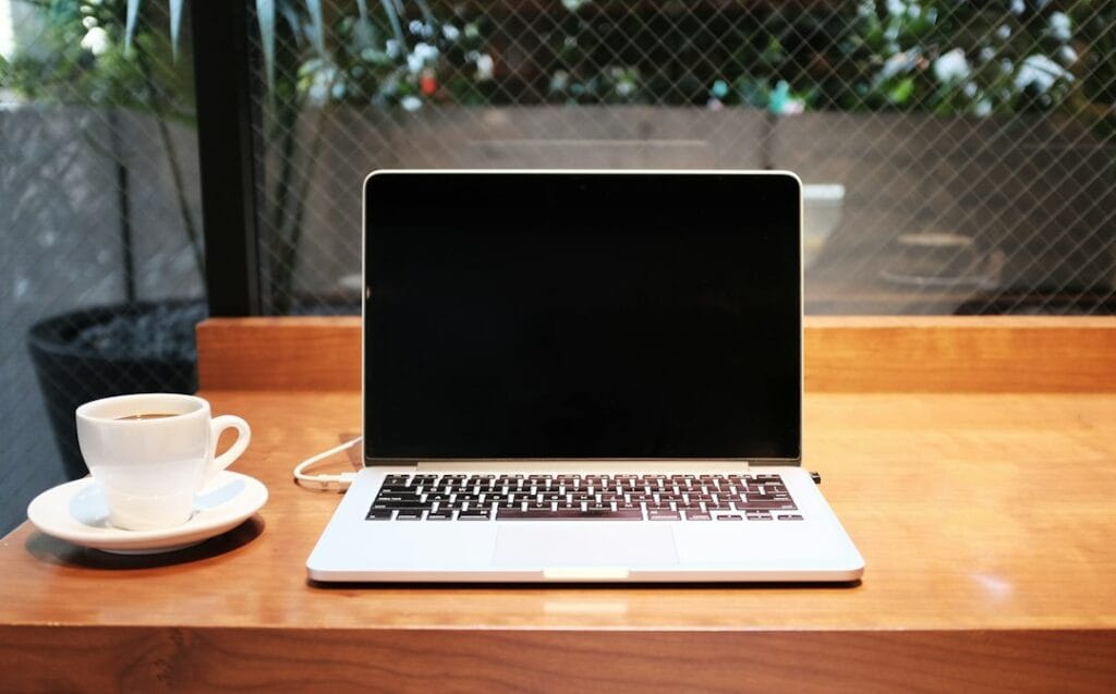 Laptop beside a coffee mug on a desk