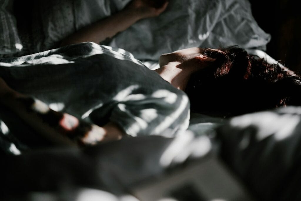 Person sleeping in bed under a blanket
