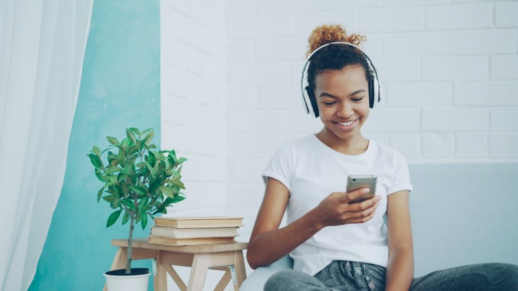 Young woman wearing headphones and using a smartphone on a couch