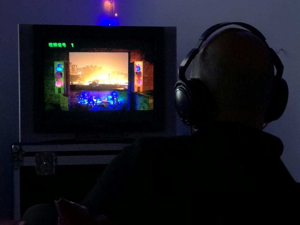 A man sitting in front of a TV wearing headphones