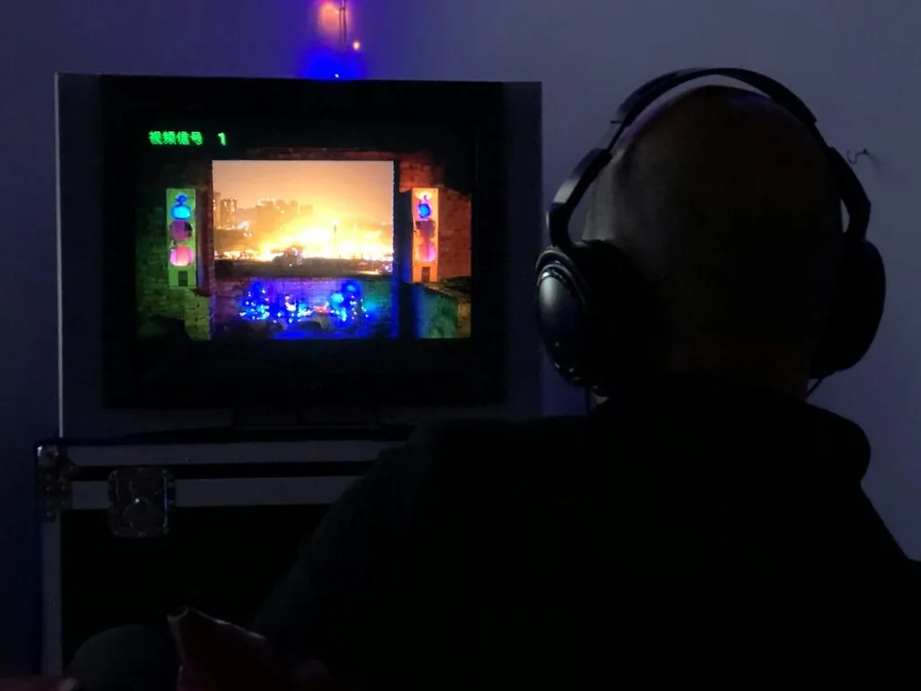 A man sitting in front of a TV wearing headphones