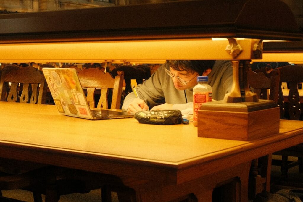 Student studying at a library table with a laptop