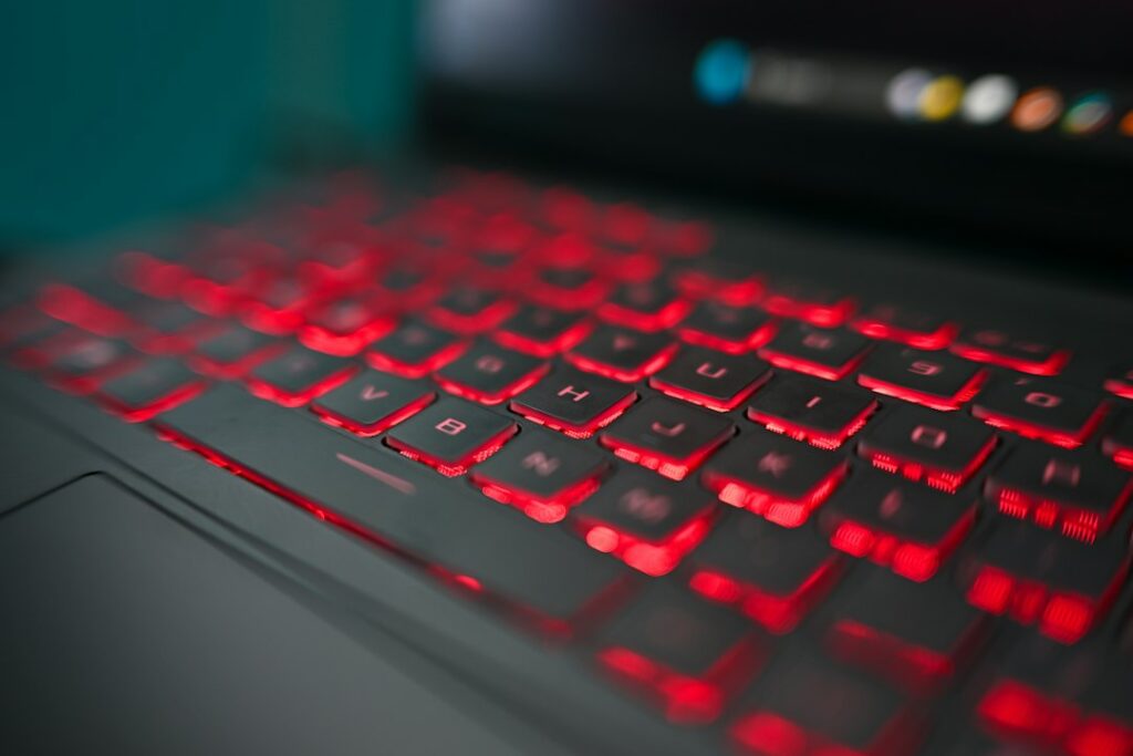 Laptop keyboard with glowing red keys in a dark room